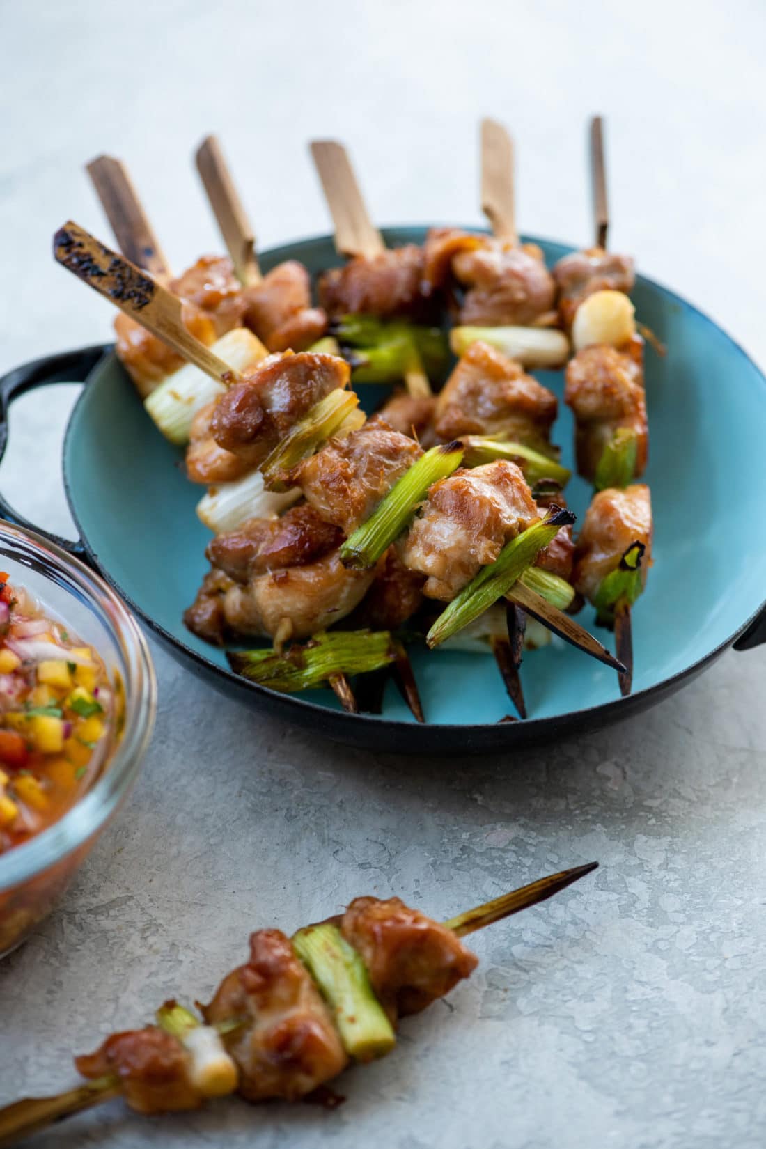 Chicken Yakitori skewers on a blue plate.