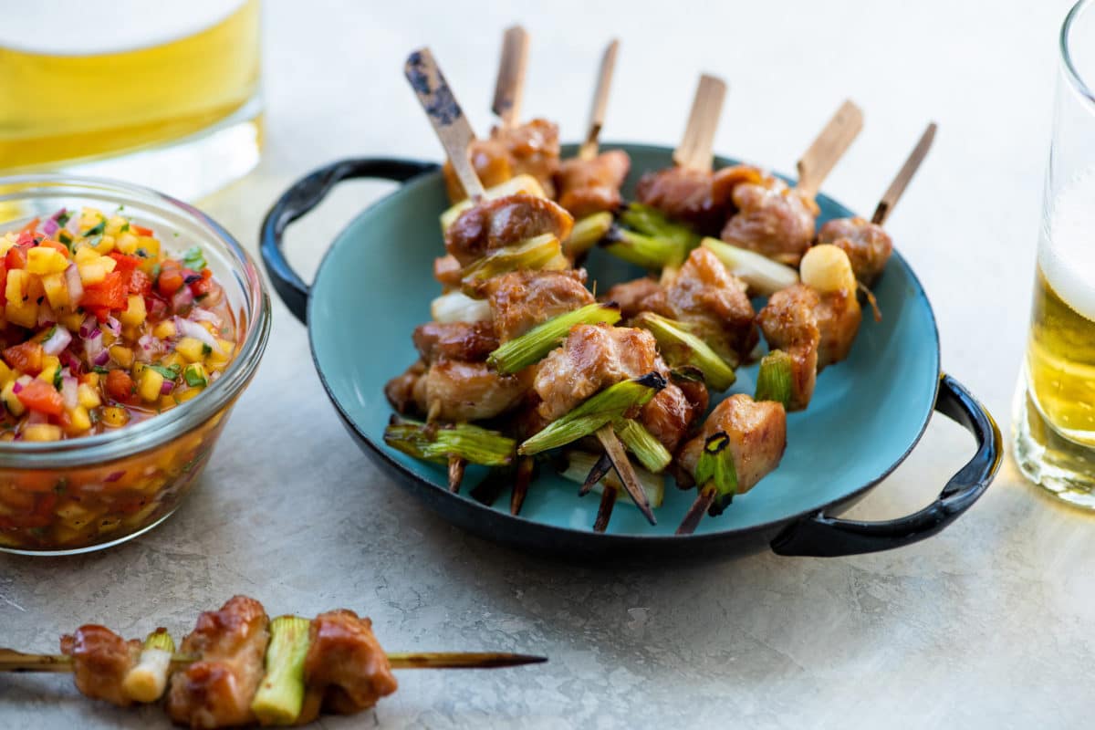 Chicken Yakitori skewers in a handled, blue bowl.