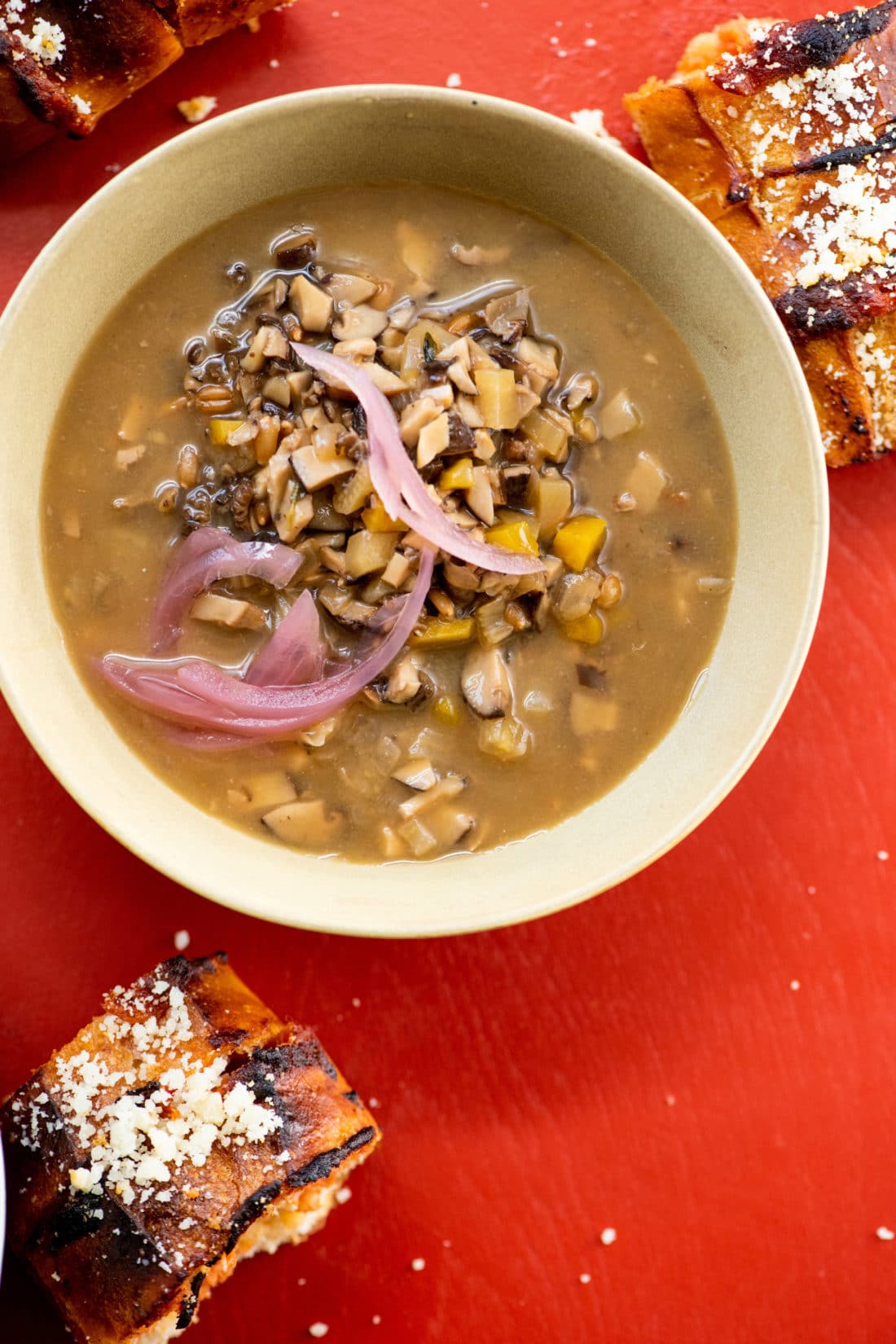 Bowl of Mushroom Spelt Soup on a red table.