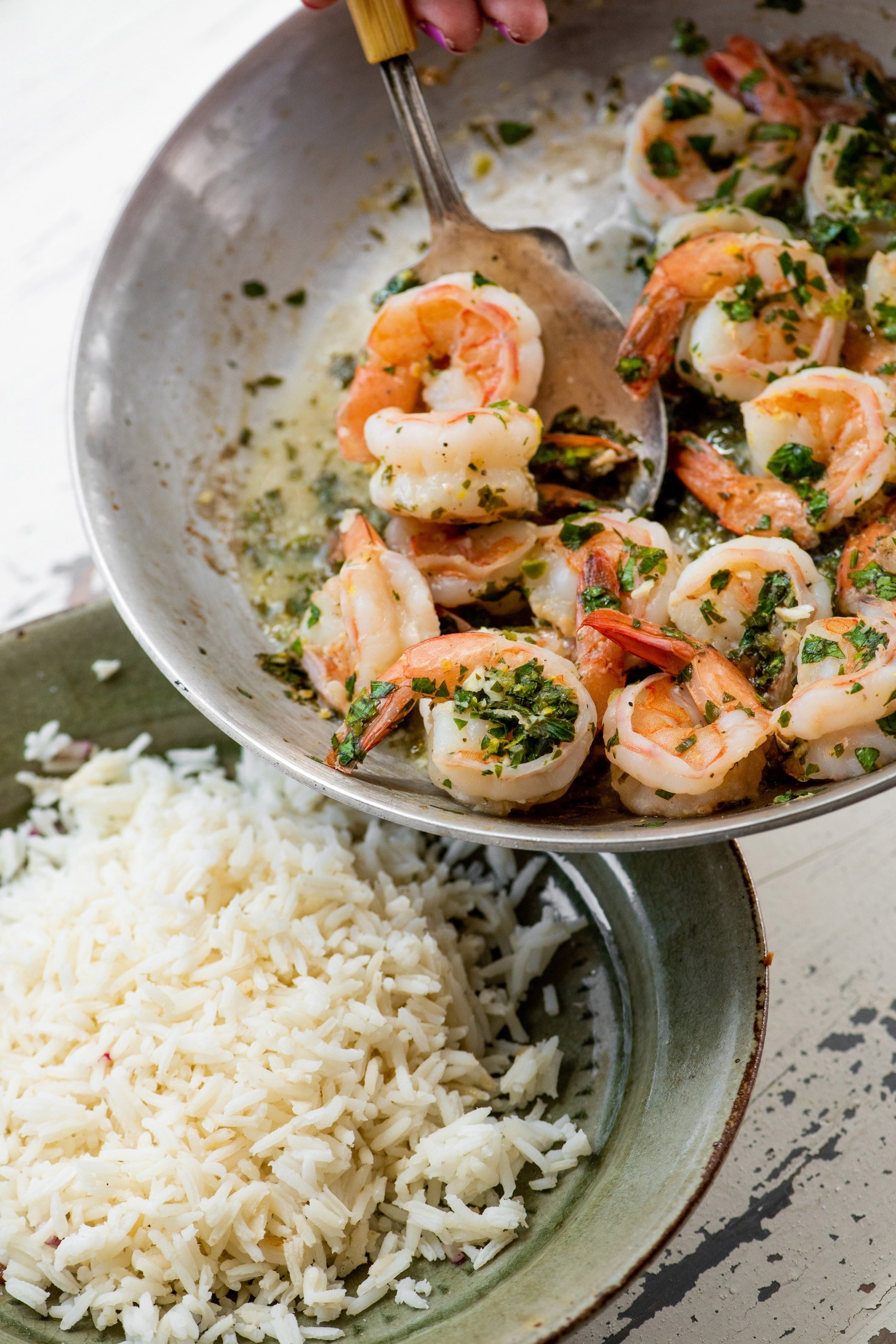 Pouring shrimp over bowl of white rice.