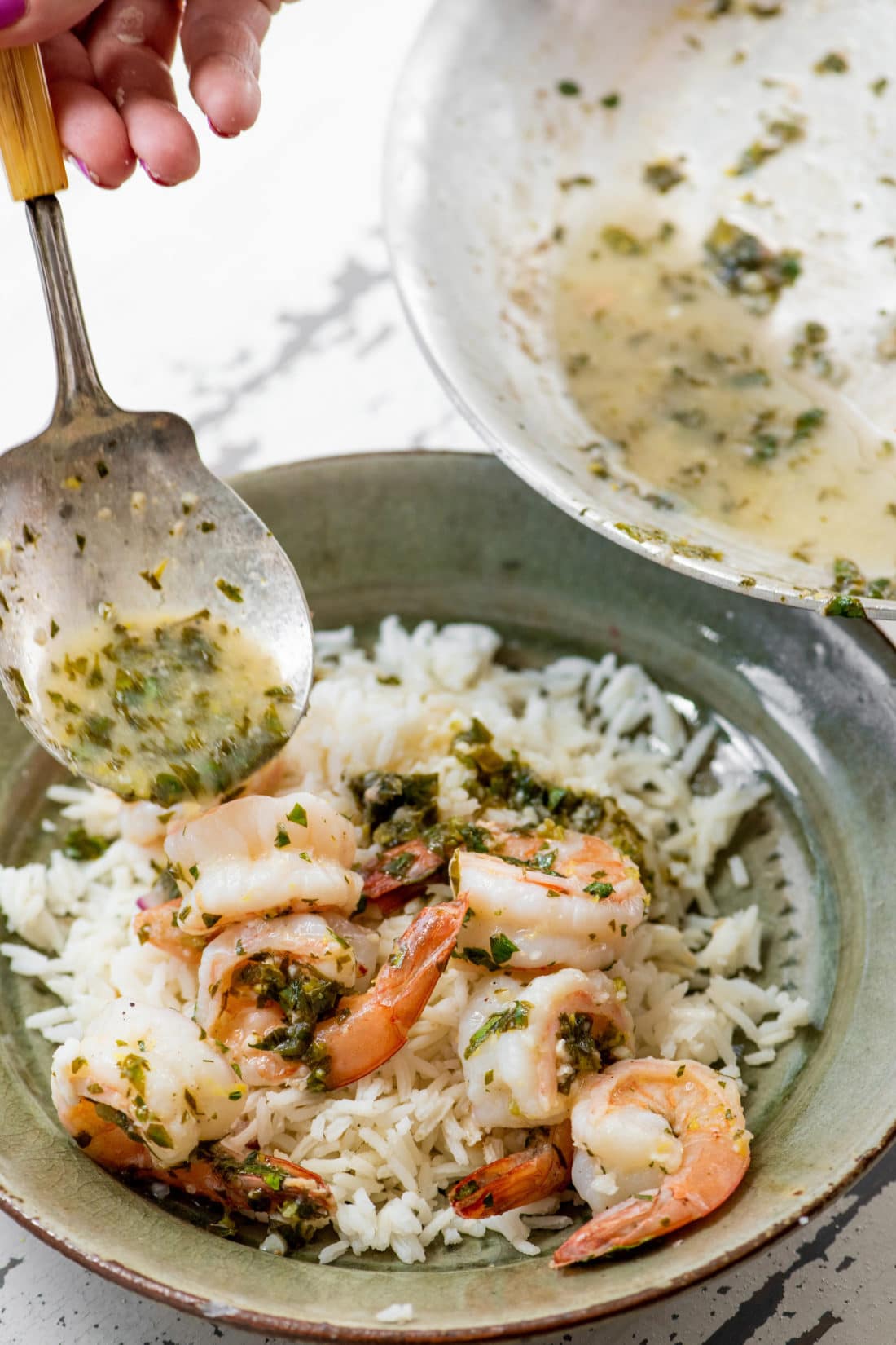 Spoon drizzling juices onto Spicy Lemon Shrimp Over Rice.