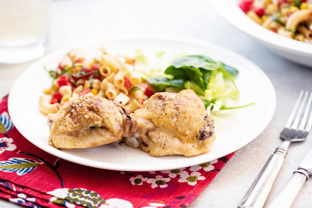 Two Chicken Thighs Stuffed With Mushrooms on a plate with noodles and salad.