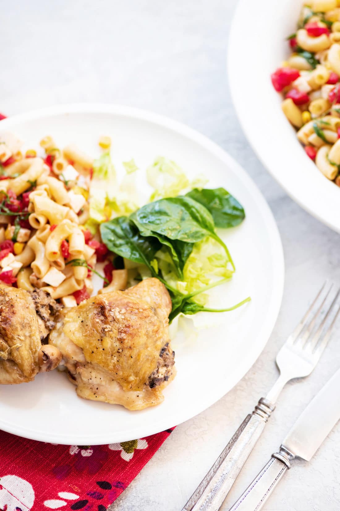 Fork next to a plate with two Chicken Thighs Stuffed With Mushrooms, salad, and noodles.