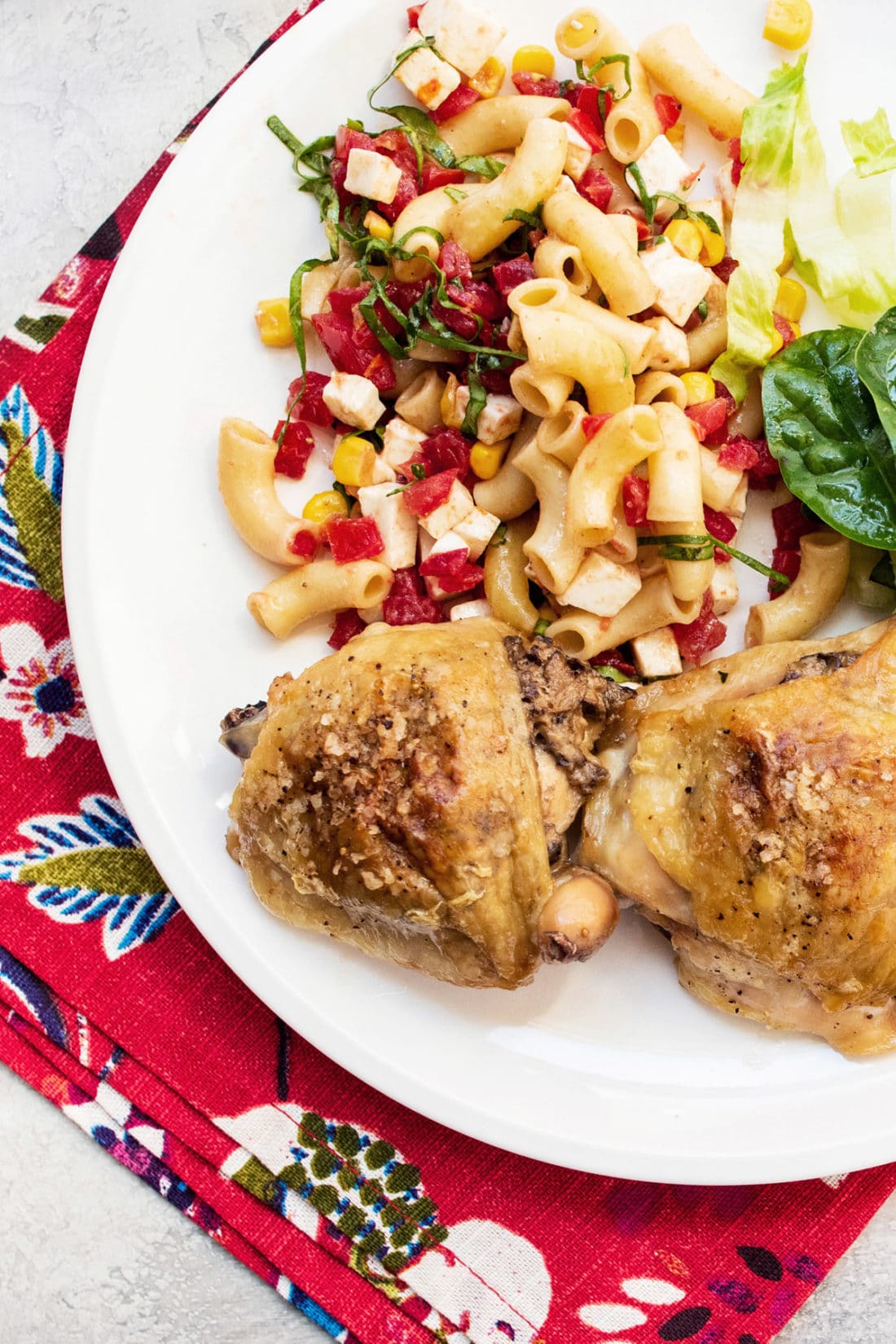 Plate with Chicken Thighs Stuffed With Mushrooms, noodles, and salad on a colorful cloth napkin.