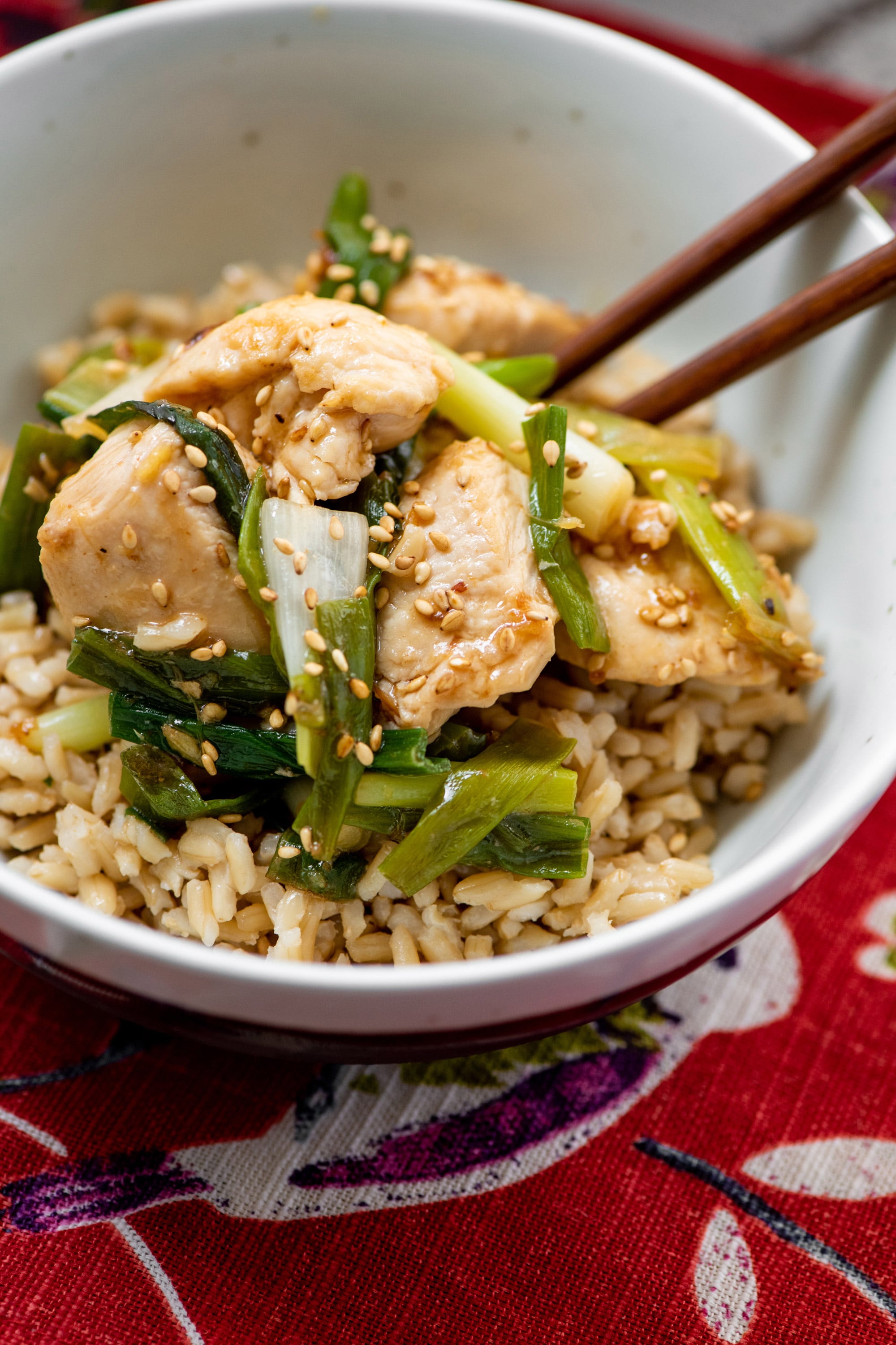 Stir Fried Chicken with Scallions in white bowl with chopsticks.