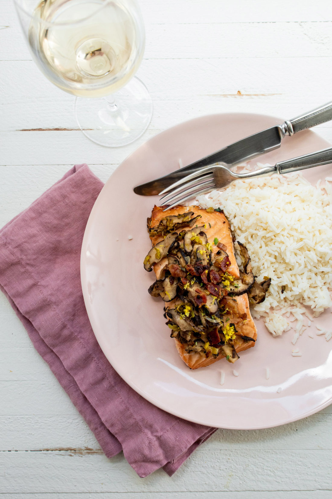 Orange Salmon with Leeks and Mushrooms on a light pink plate with rice.