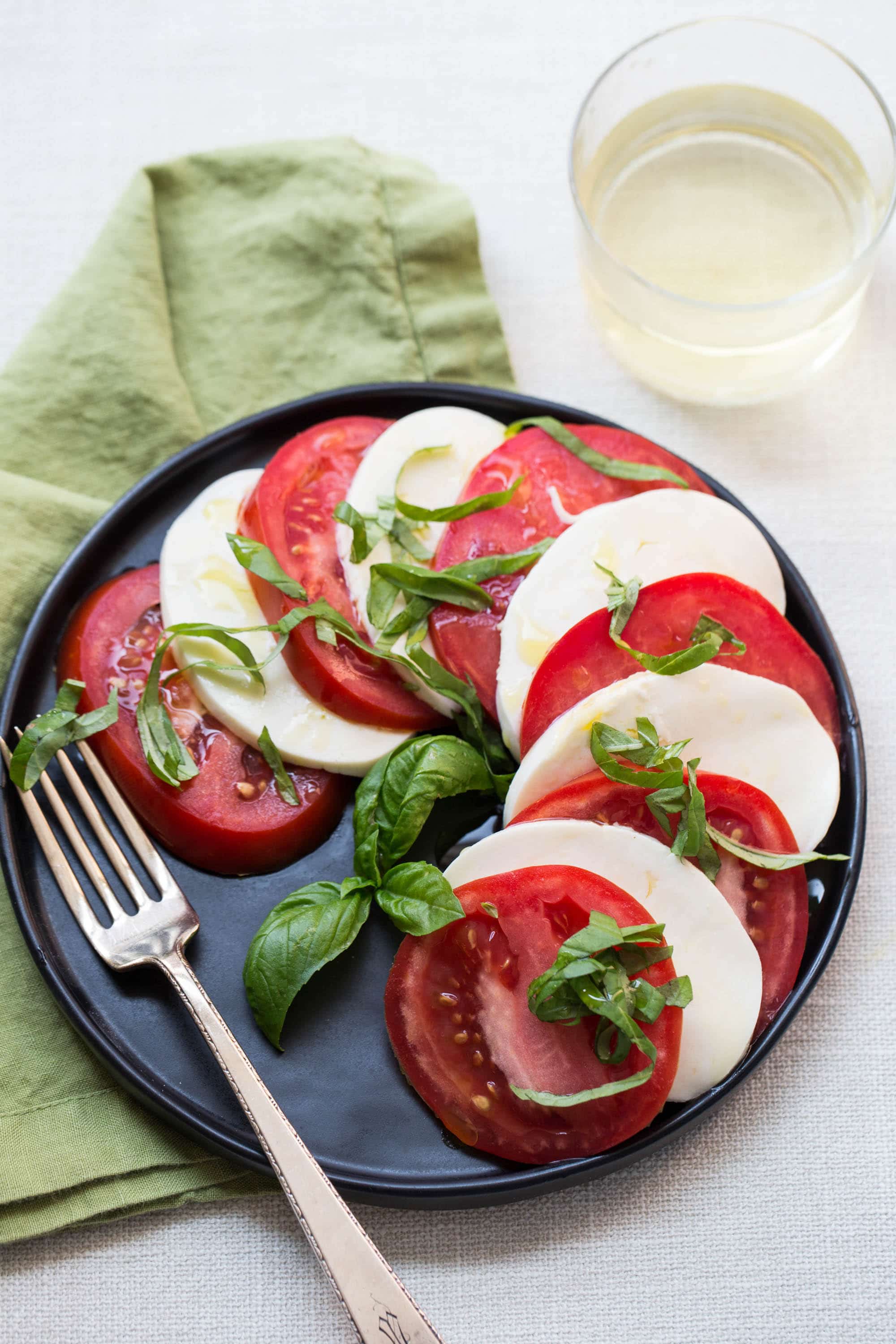 Tomato and Mozzarella Caprese Salad on a black plate with a fork.