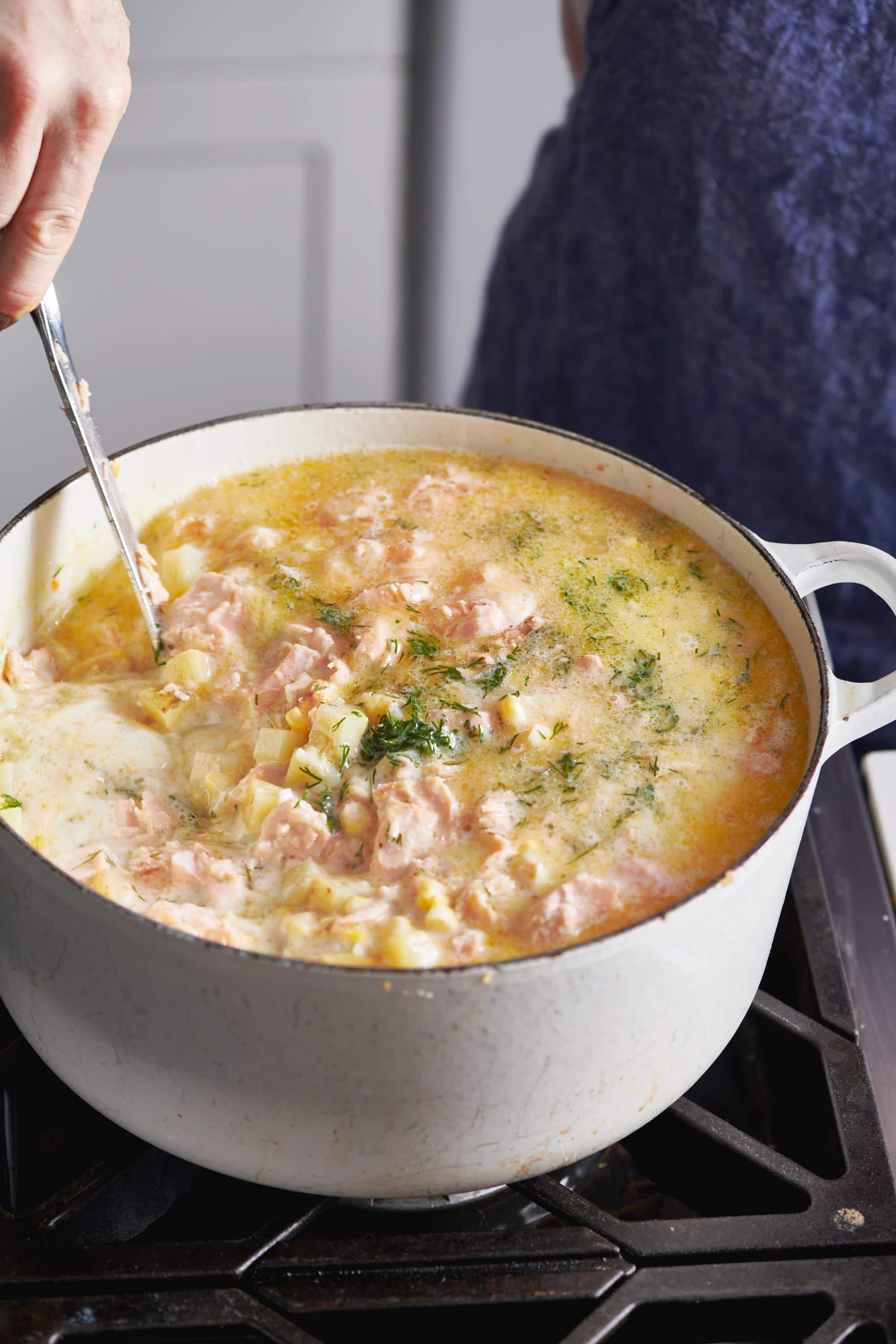 Woman stirring pot of chowder on the stove.