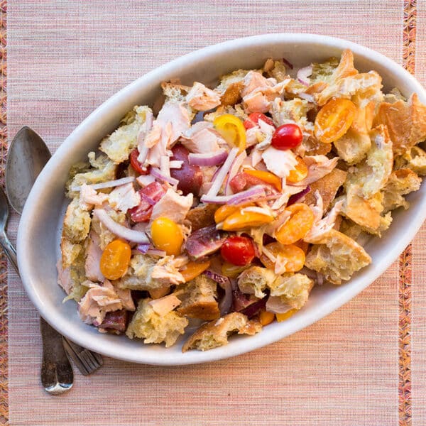 Salmon Panzanella in white serving dish on table.