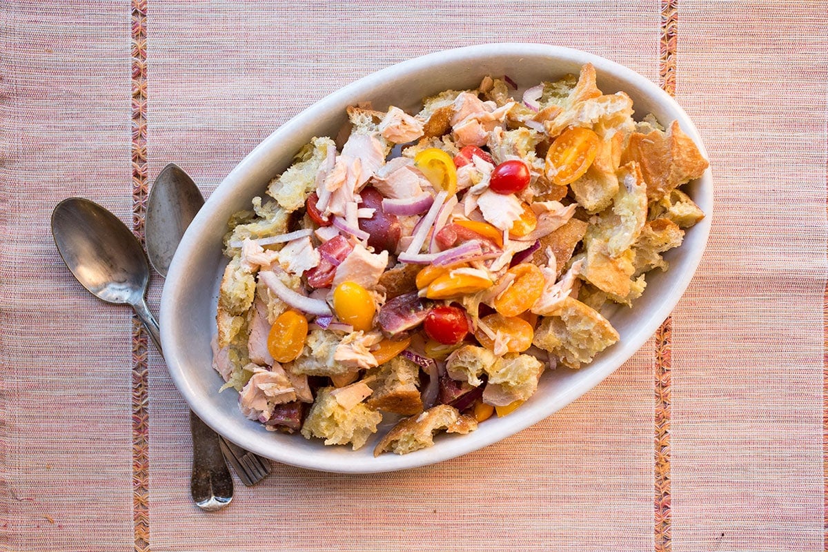 Salmon Panzanella in white serving dish on table.