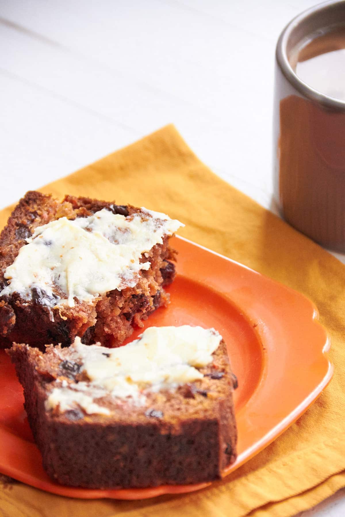 Slices of Carrot Raisin Bread with butter on orange plate.