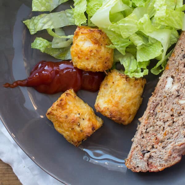 Cauliflower tots on grey plate with meatloaf and salad.