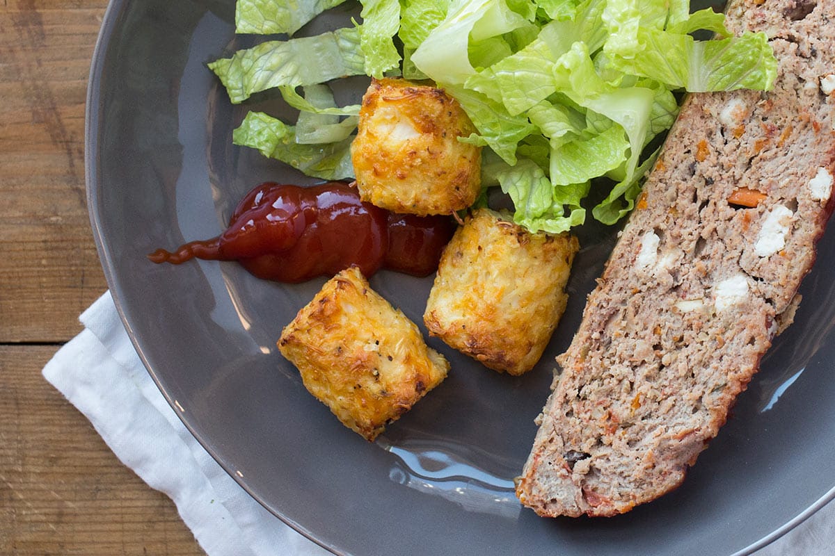 Cauliflower tots on grey plate with meatloaf and salad.