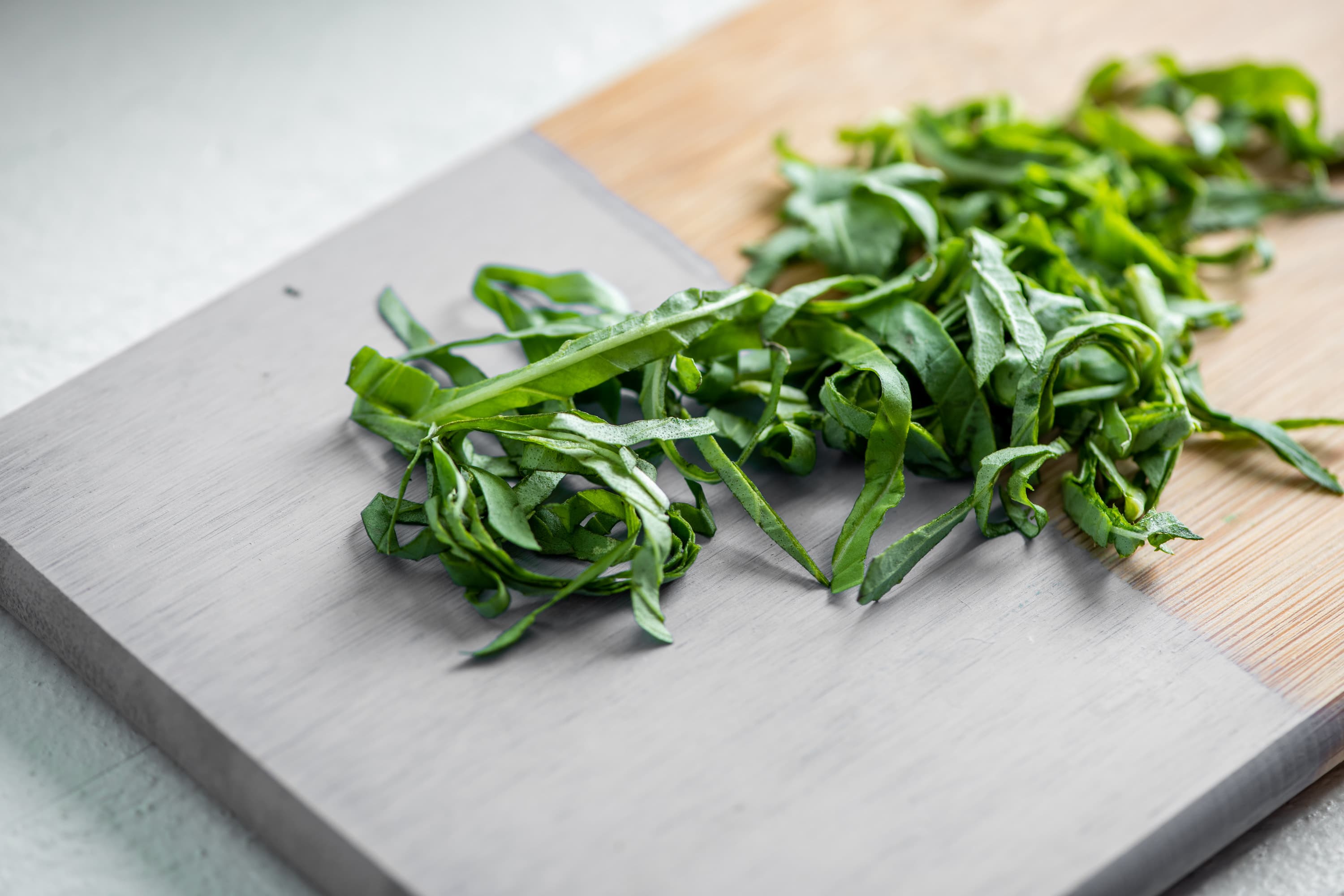 Thinly sliced or chiffonaded basil on a painted cutting baord.