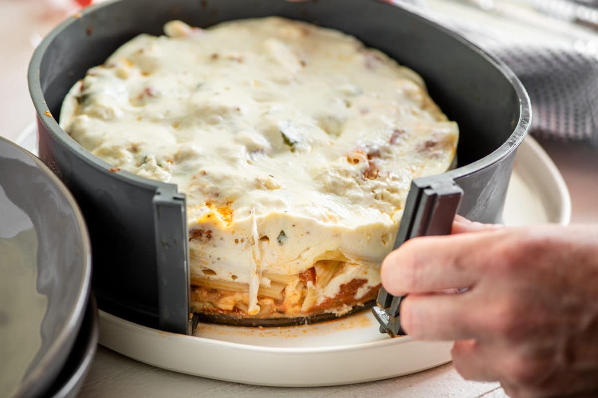 Person unmolding a springform pan from ziti \"lasagna.\"