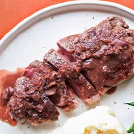 Classic strip steak Diane on plate with green beans and potatoes.