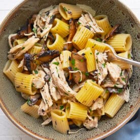 Simple chicken and pasta dish with Marsala wine sauce in brown bowl on table.