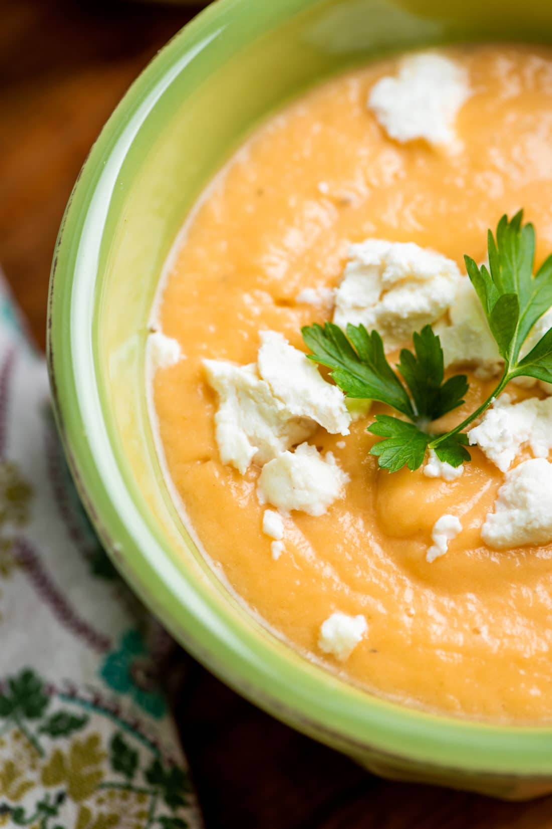 Goat cheese and parsley on a bowl of Creamy Rutabaga, Carrot and Parsnip Soup.