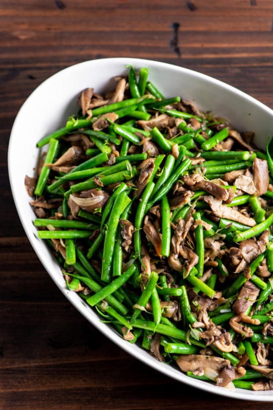 White serving dish of Green Beans and Mushrooms with Shallots.