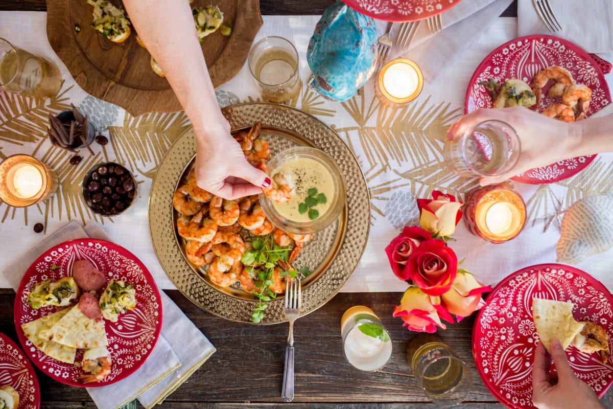 Woman dipping shrimp into sauce on festive holiday table.