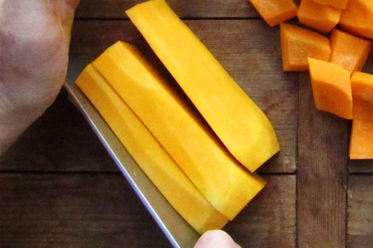 Cubing butternut squash on cutting board.