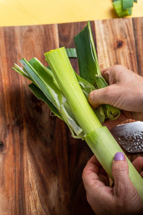 Woman removing the outer leaves from a leek.