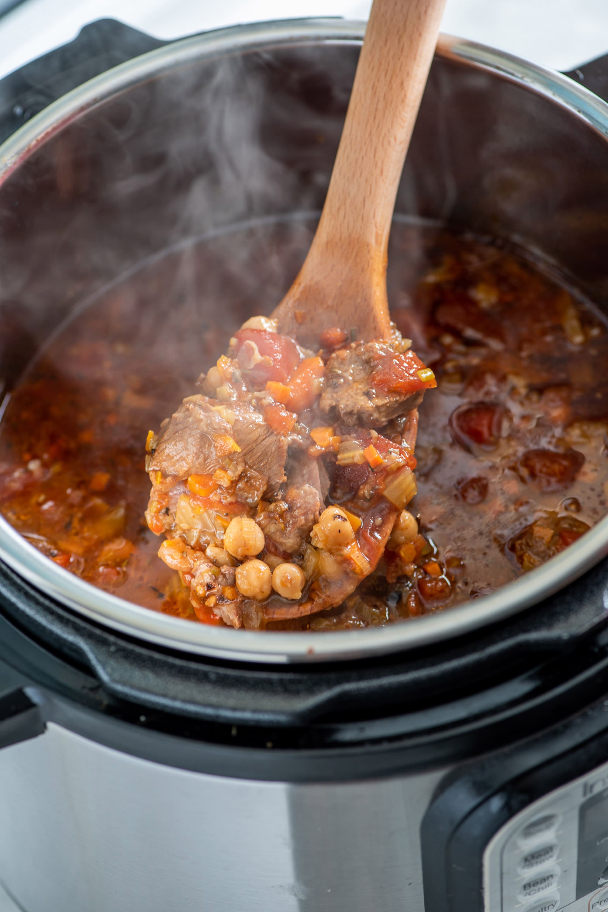 Wooden ladle scooping Mediterranean Lamb Stew from an Instant Pot.