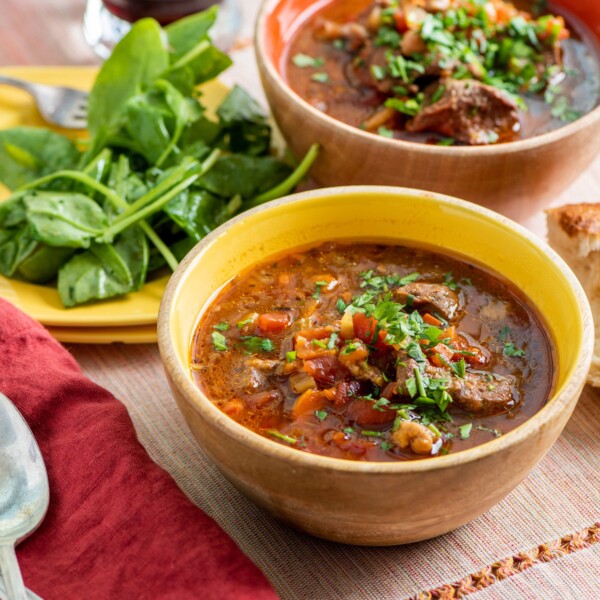 Bowls of Mediterranean Lamb Stew with a plate of spinach.
