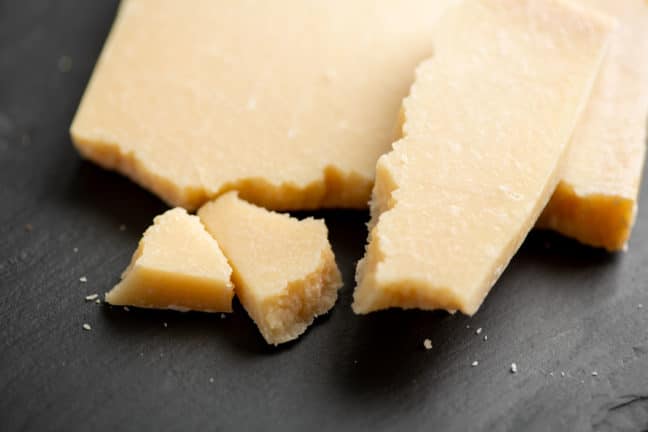 Pieces of Parmesan Cheese on a black surface.