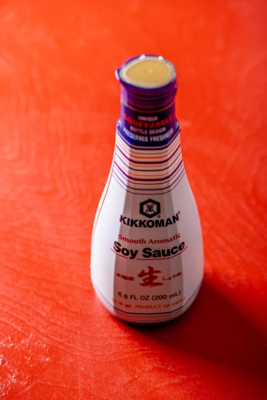 Jar of Kikkoman Soy Sauce on red table.