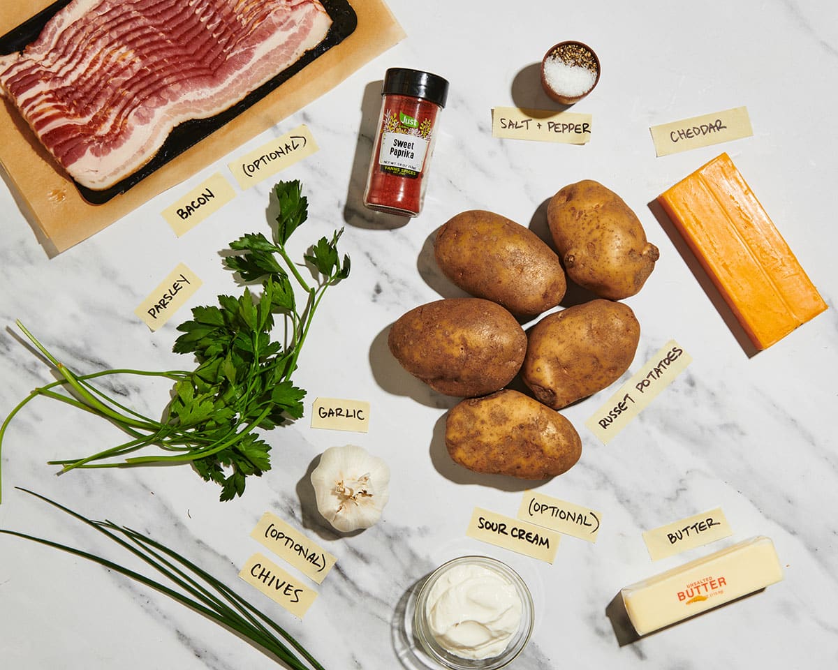 Potatoes, bacon, chees, fresh herbs, and other ingredients for hasselback potatoes.