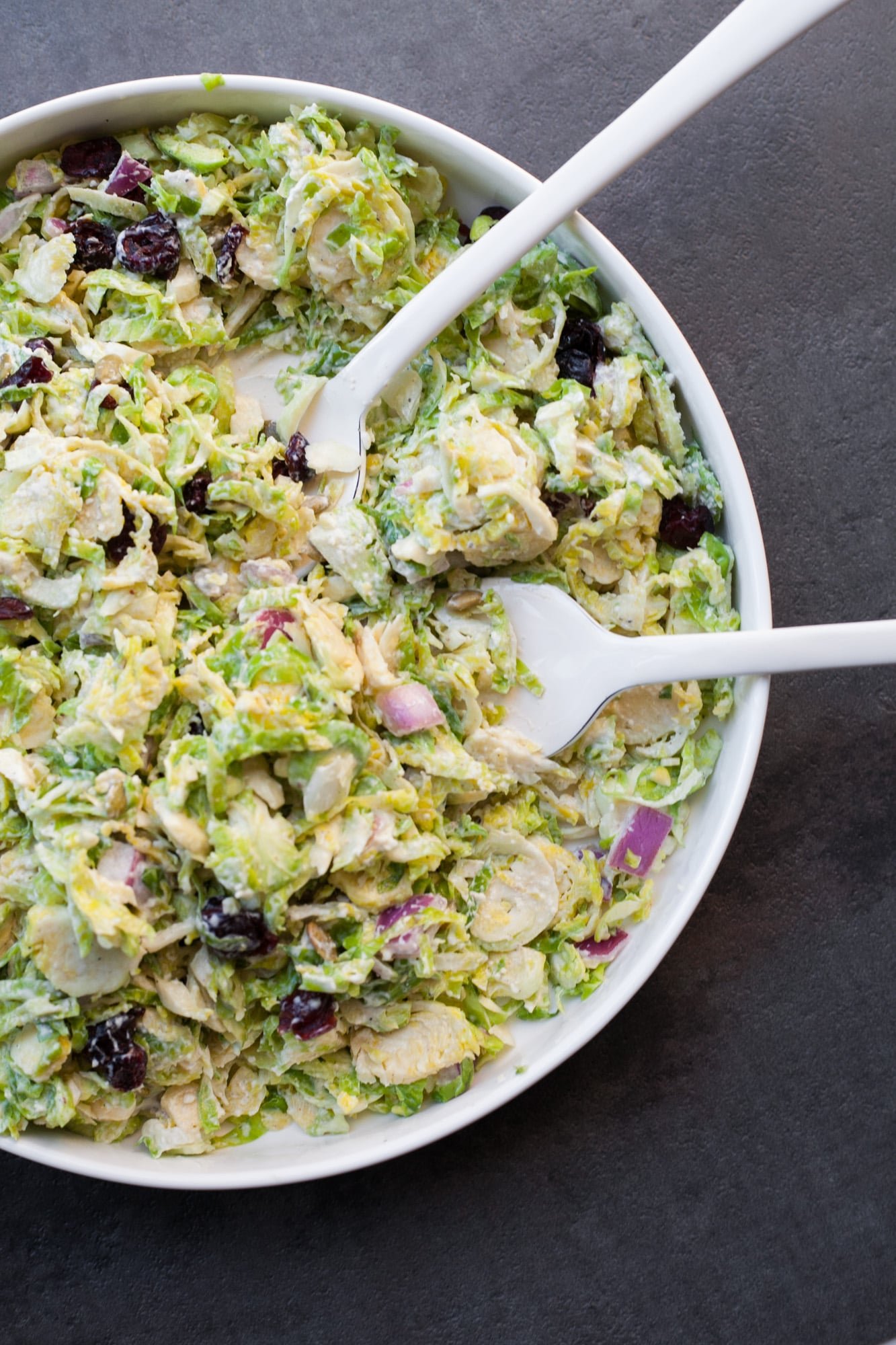 Creamy Brussels Sprouts Slaw in a shite bowl with a serving fork.