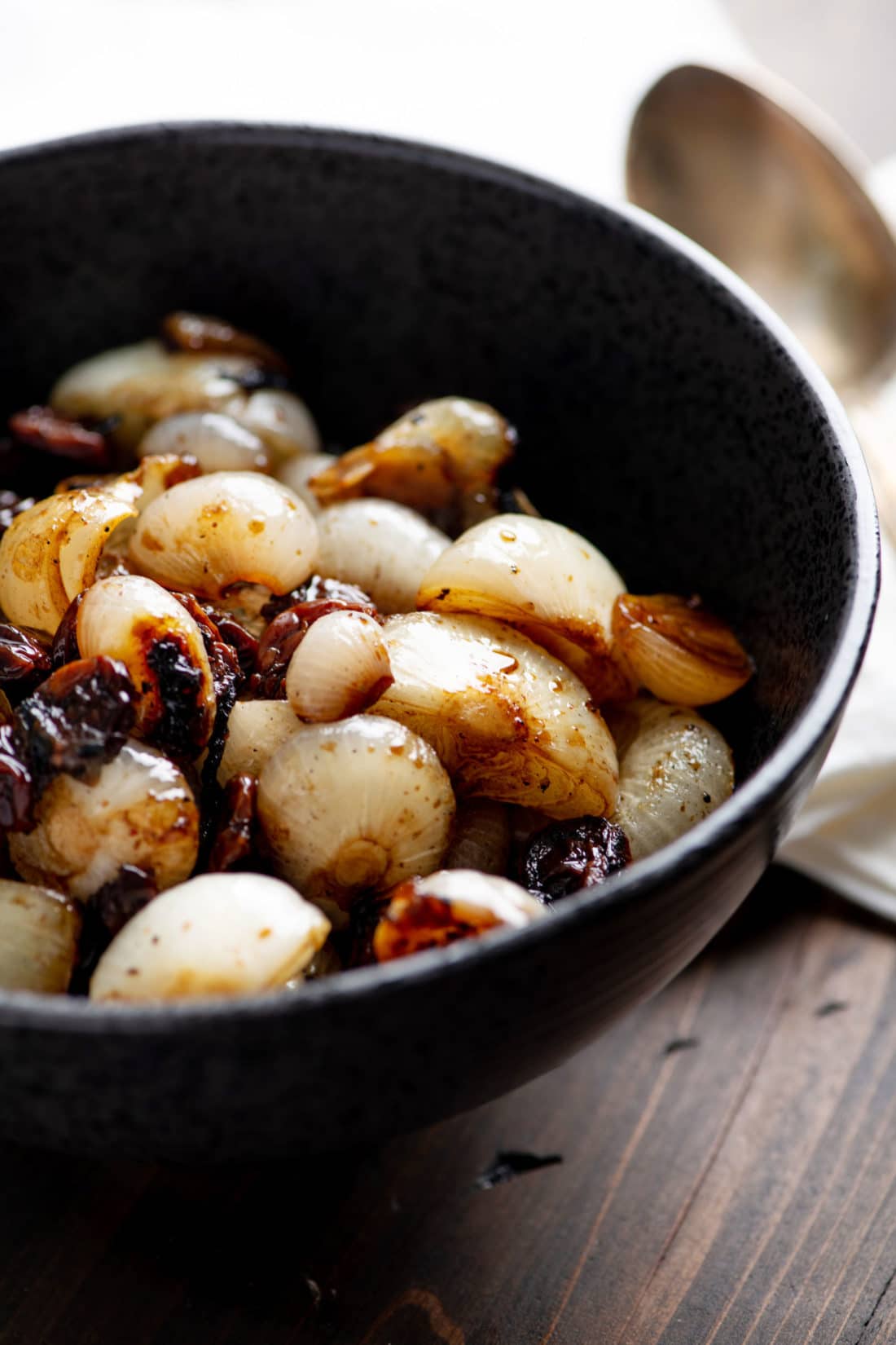 Braised Cipollini Onions with Dried Cherries in a black bowl.