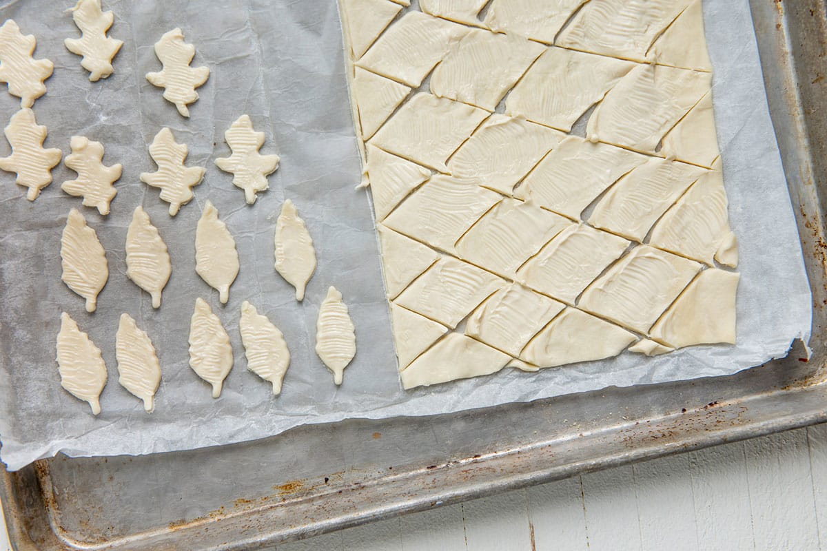 Leaf and diamond shaped puff pastry on baking sheet.