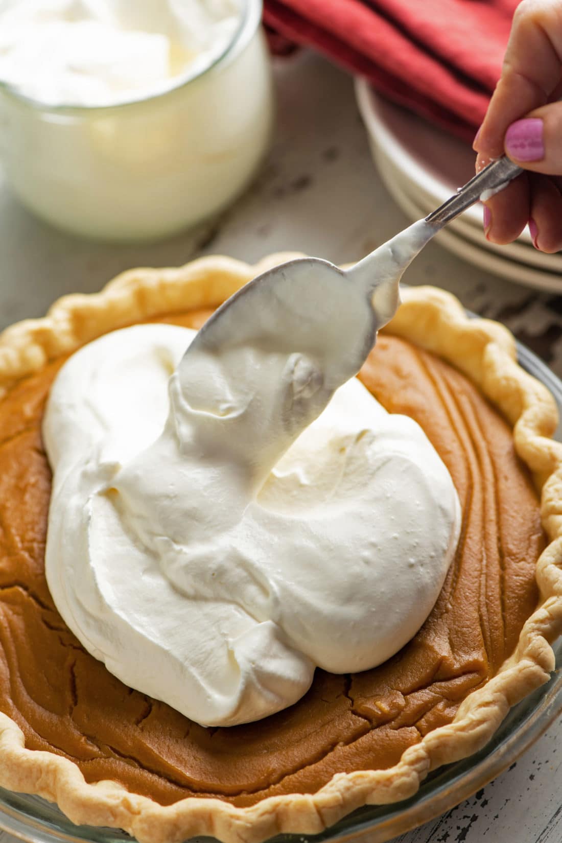 Spoon scooping whipped cream onto a Salted Butterscotch Pie.