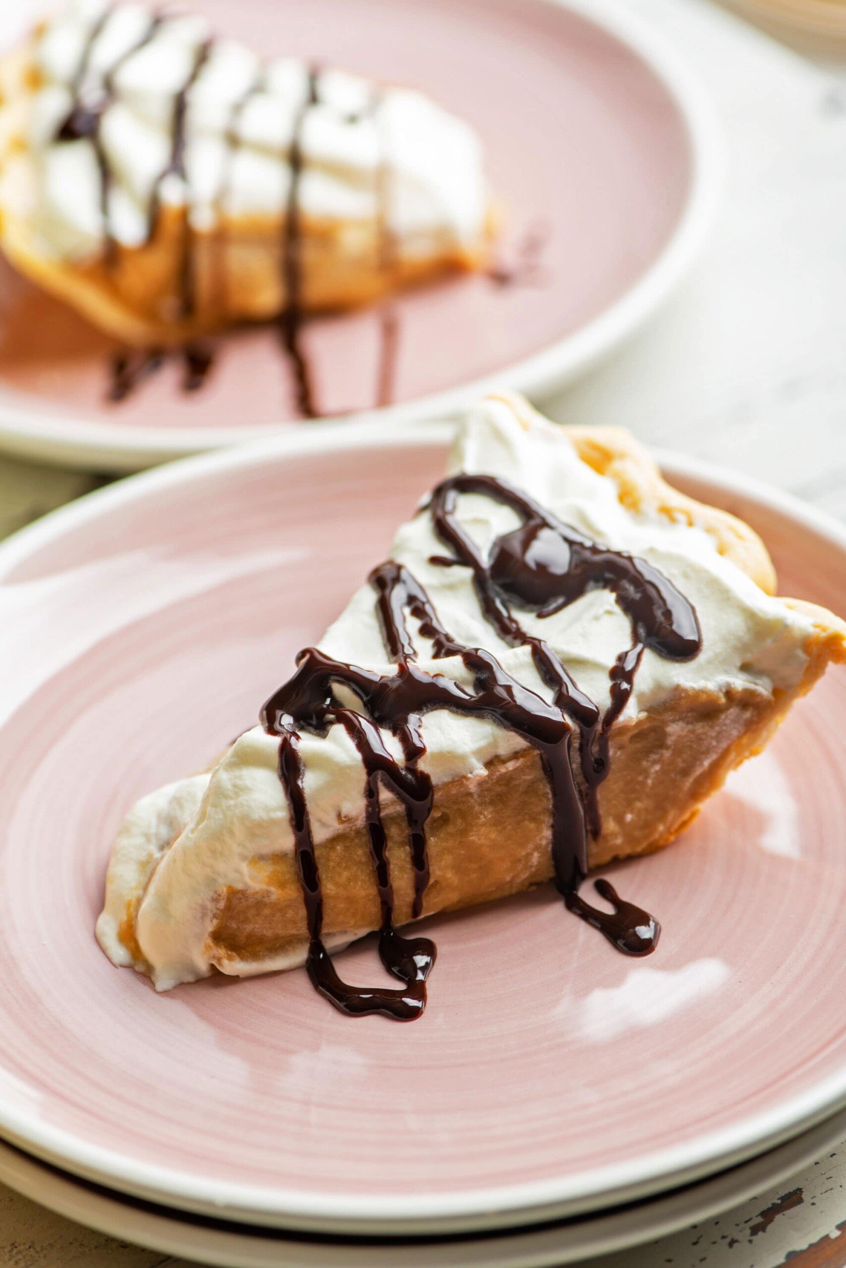 Slice of Salted Butterscotch Pie drizzled with chocolate sauce.