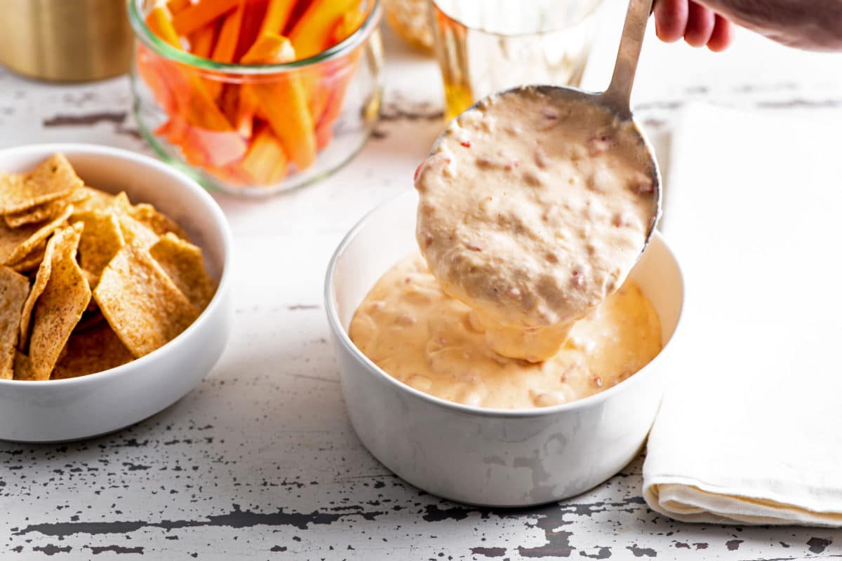 Ladle scooping Hot Pimento Cheese Dip into a bowl.