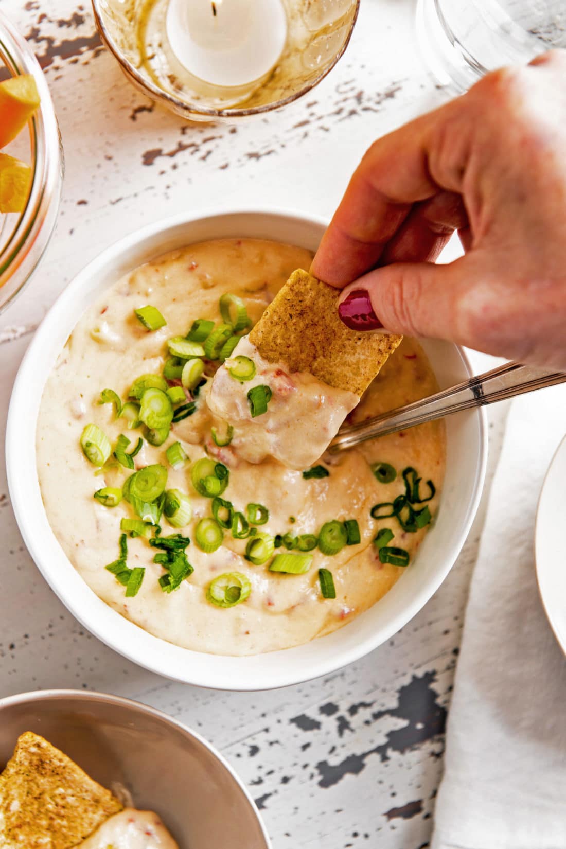 Woman dipping a chip into a bowl of Hot Pimento Cheese Dip.