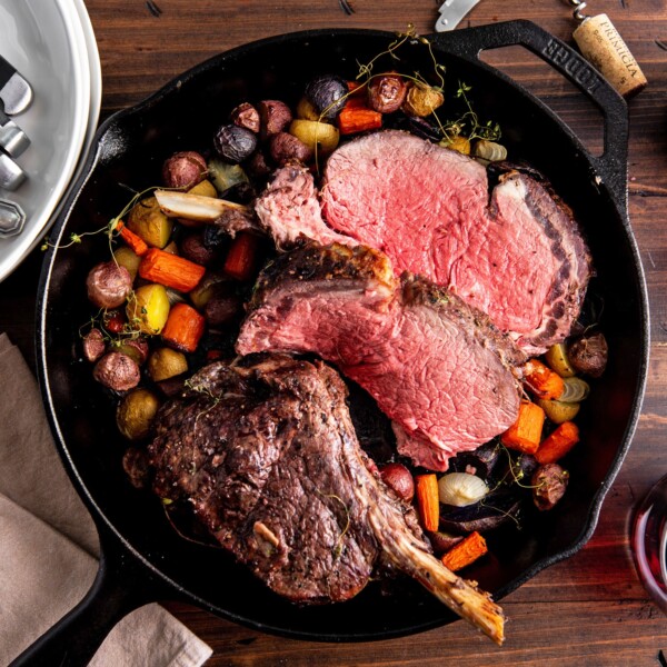 Skillet of Standing Rib Roast and vegetables on a table.