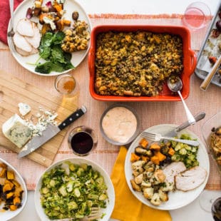 Table set with stuffing, brussels sprouts, and plates full of food.