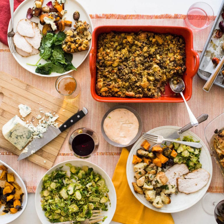 Table set with stuffing, brussels sprouts, and plates full of food.