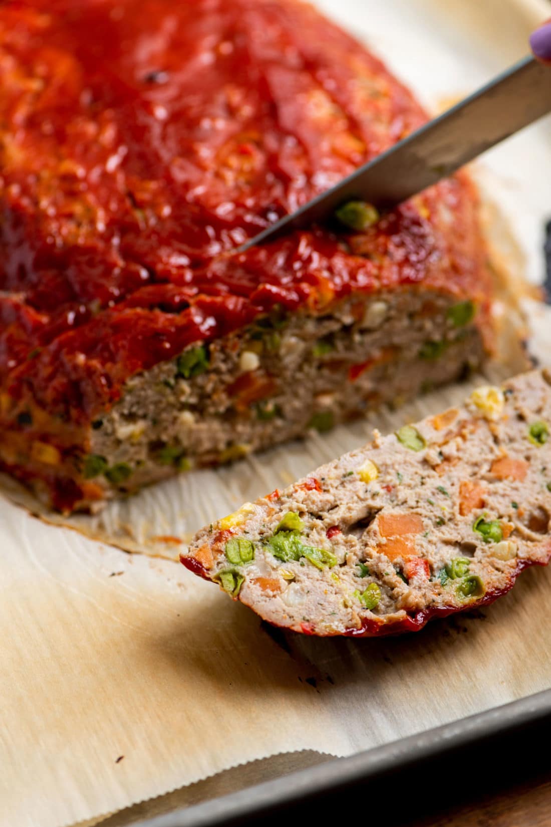 Knife slicing a Vegetable Studded Turkey Meatloaf.