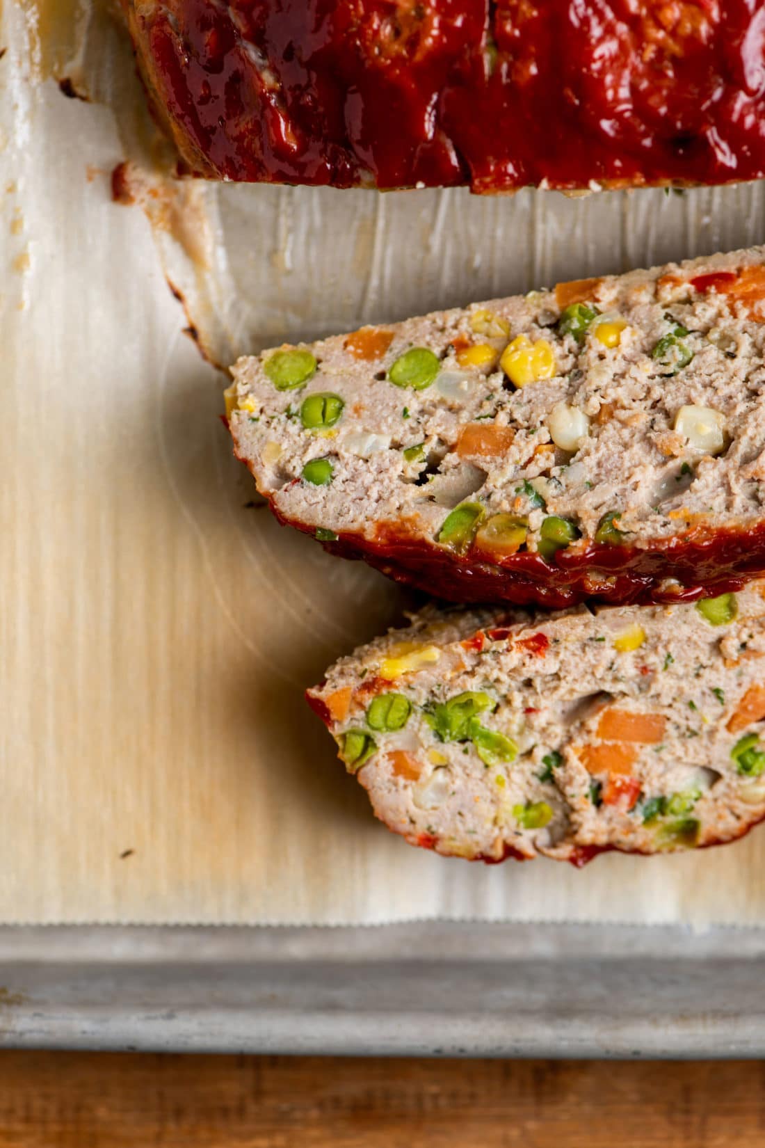 Slices of Vegetable Studded Turkey Meatloaf on parchment paper.