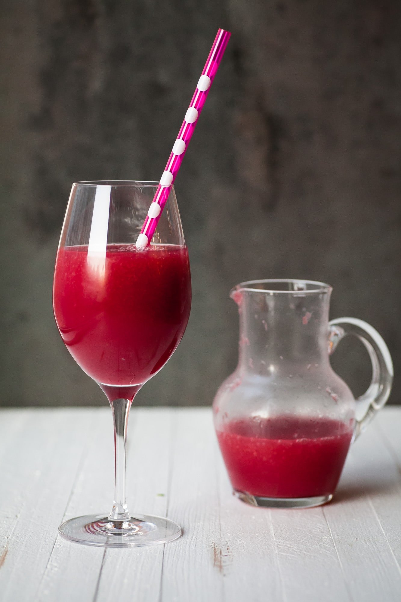Frozen Pomegranate and Citrus Cocktail in wine glass with straw.