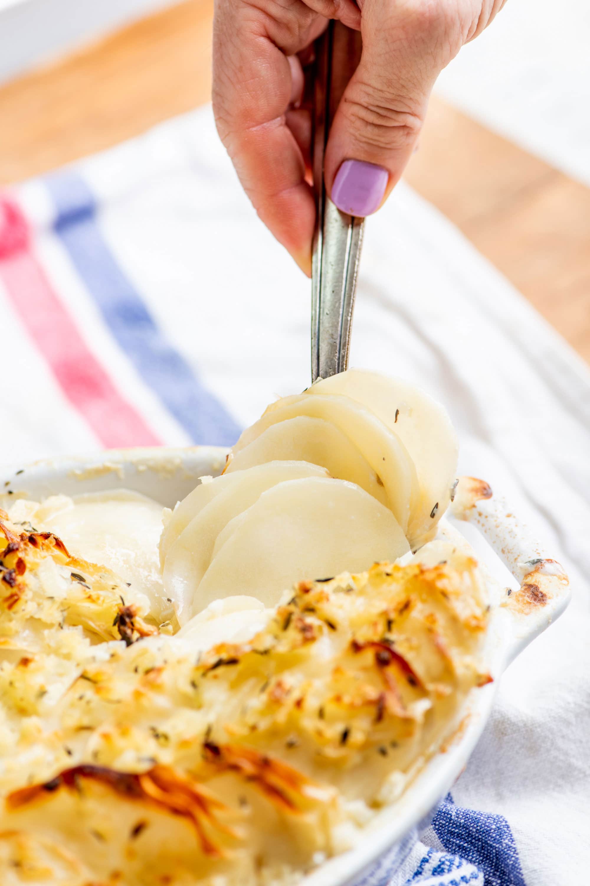 Spoon lifting a serving of Homemade Scalloped Potatoes.