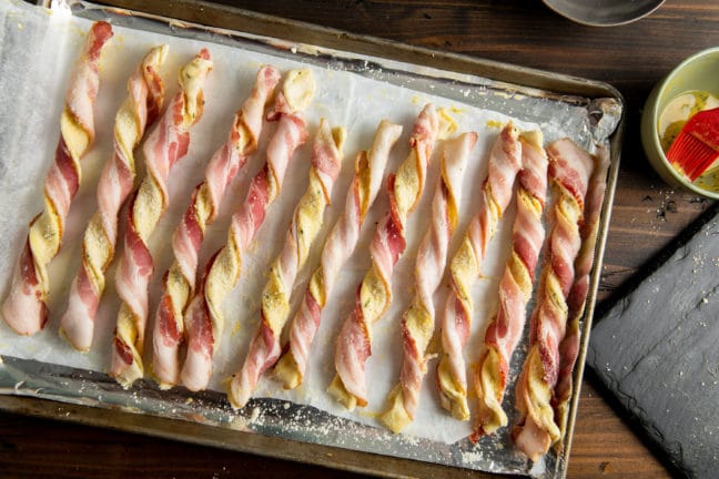 Lined baking tray of uncooked Herbed Cheesy Puff Pastry Bacon Straws.