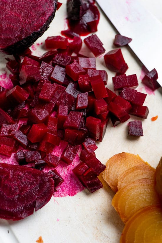 Sliced red and golden beets on a cutting board with a knife