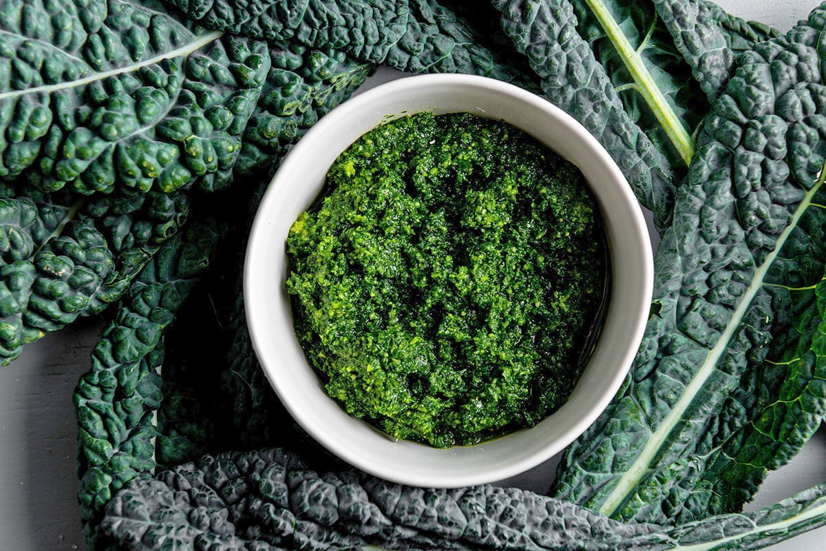 White bowl of deep green Kale Pesto.