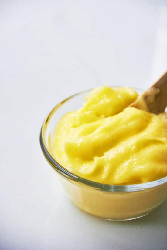 Wooden spoon in a glass bowl of Lemon Curd.