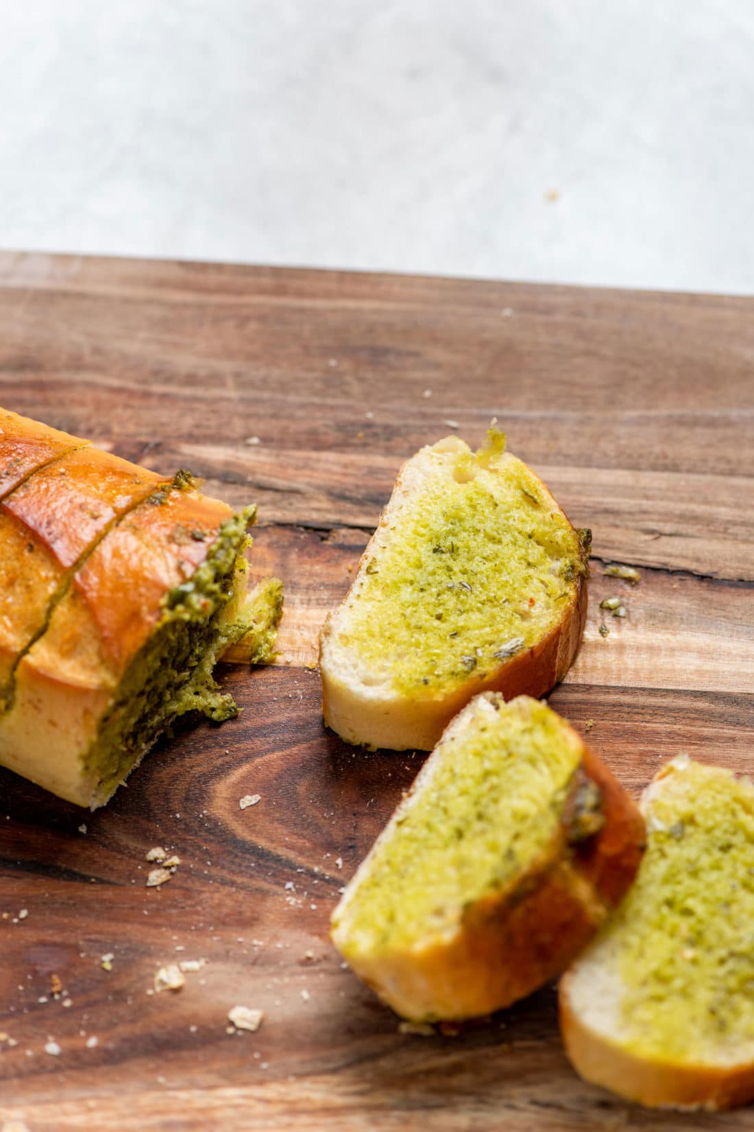 Slices of Salsa Verde Garlic Bread on a wooden surface.